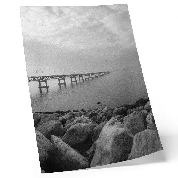 Impression sur toile paysage paisible représentant un pont sur une plage rocheuse sous un ciel gris