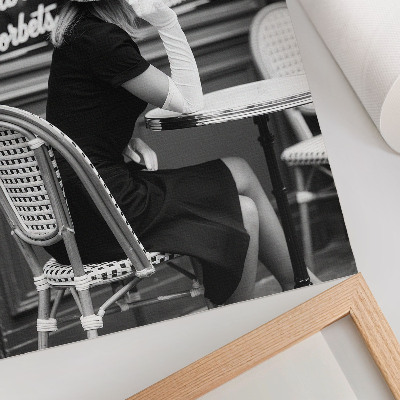 Affiche décorative Une femme portant un chapeau, assise à une table dans un café