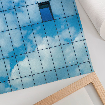 Impression sur toile Une façade de verre reflétant le ciel et les nuages