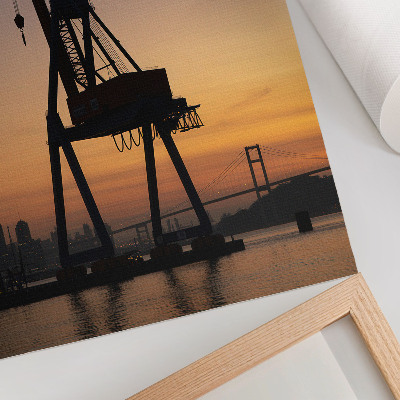 Impression sur toile Silhouette de grue industrielle au coucher du soleil sur le pont