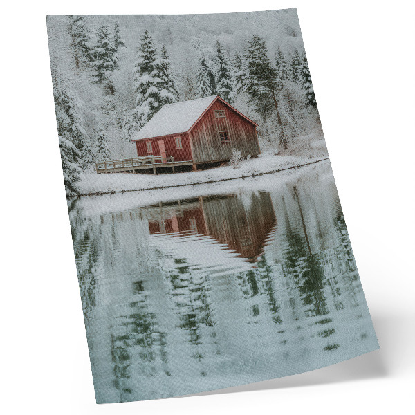 Impression sur toile Un chalet rouge parmi les arbres enneigés au bord de l'eau