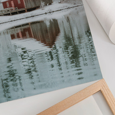 Impression sur toile Un chalet rouge parmi les arbres enneigés au bord de l'eau