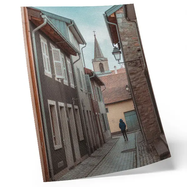 Impression sur toile rue étroite avec immeubles de rapport et tour, manteau bleu