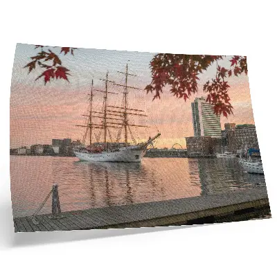 Affiche un voilier au coucher du soleil dans un panorama paisible de la ville