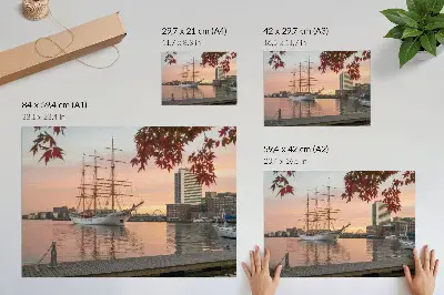 Affiche un voilier au coucher du soleil dans un panorama paisible de la ville