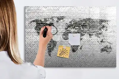 Tableau magnétique représentant une carte du monde sur un mur de briques