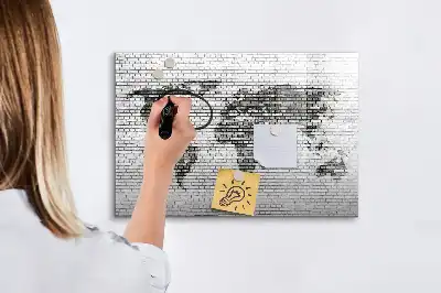 Tableau magnétique représentant une carte du monde sur un mur de briques