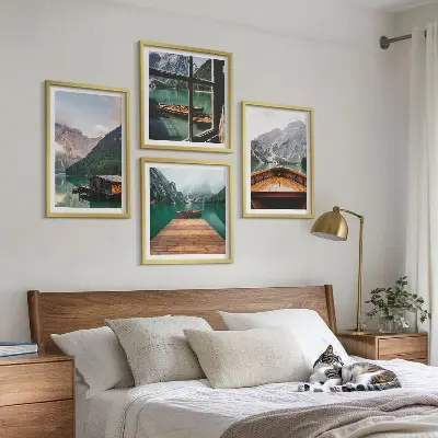 Mur de tableaux représentant des paysages de montagne avec des chalets et des bateaux