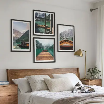 Mur de tableaux représentant des paysages de montagne avec des chalets et des bateaux