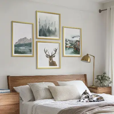 Mur de tableaux représentant des montagnes, un lac, un cerf, une cabane et du brouillard