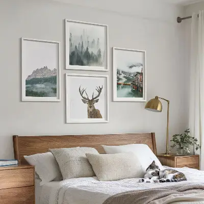 Mur de tableaux représentant des montagnes, un lac, un cerf, une cabane et du brouillard
